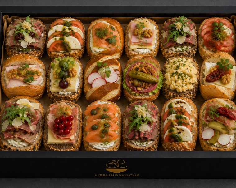 Schwarze Lieblingsküche-Box mit achtzehn belegten Brötchen, in Reihen gelegt.
